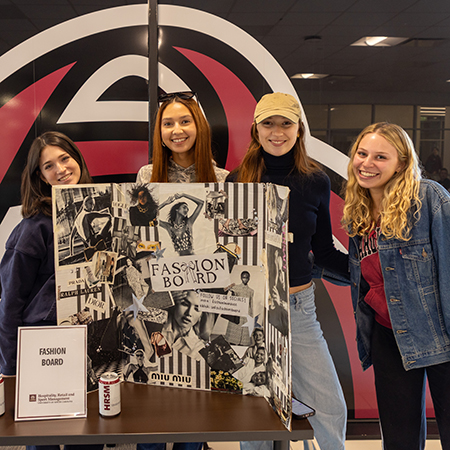 Four members of USC Fashion Board pose at a student organization fair