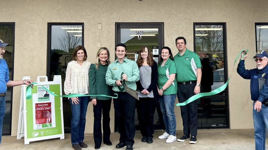 Group of people cutting a ceremonial ribbon outside of a building