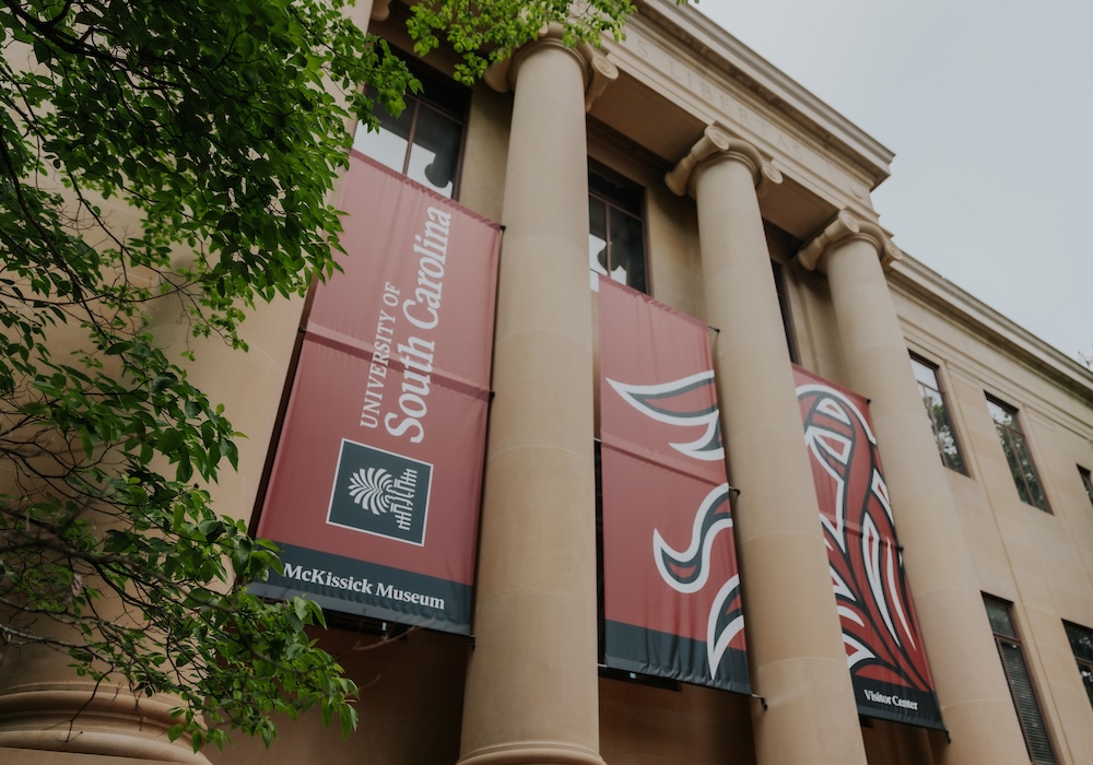Beige building with columns with sign that reads university of south carolina, mckissick museum, visitor center