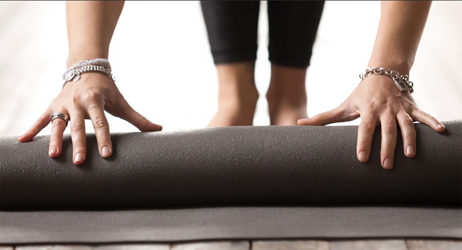 Hands unrolling yoga mat for a workout