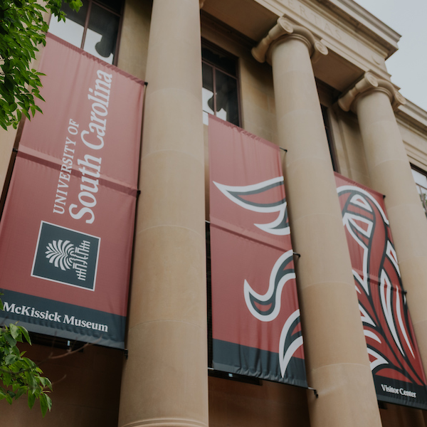 Beige building with columns with sign that reads university of south carolina, mckissick museum, visitor center