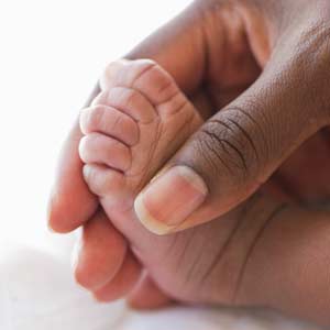 A close-up of a baby’s foot in its mother’s hand.