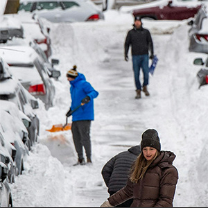 People work to dig out their cars on a snowy street.