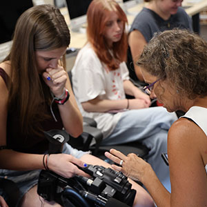 Female instructor helping a female student with a film camera.