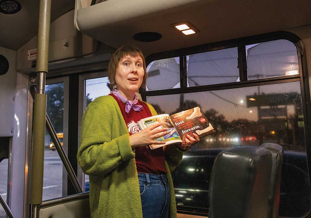 Margaret Jackson prepares student volunteers for a school visit from the front of the Cocky’s Reading Express bus.